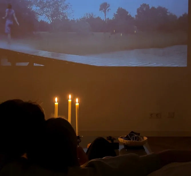 Stel op de bank bij kaarslicht, met een film groot op de muur