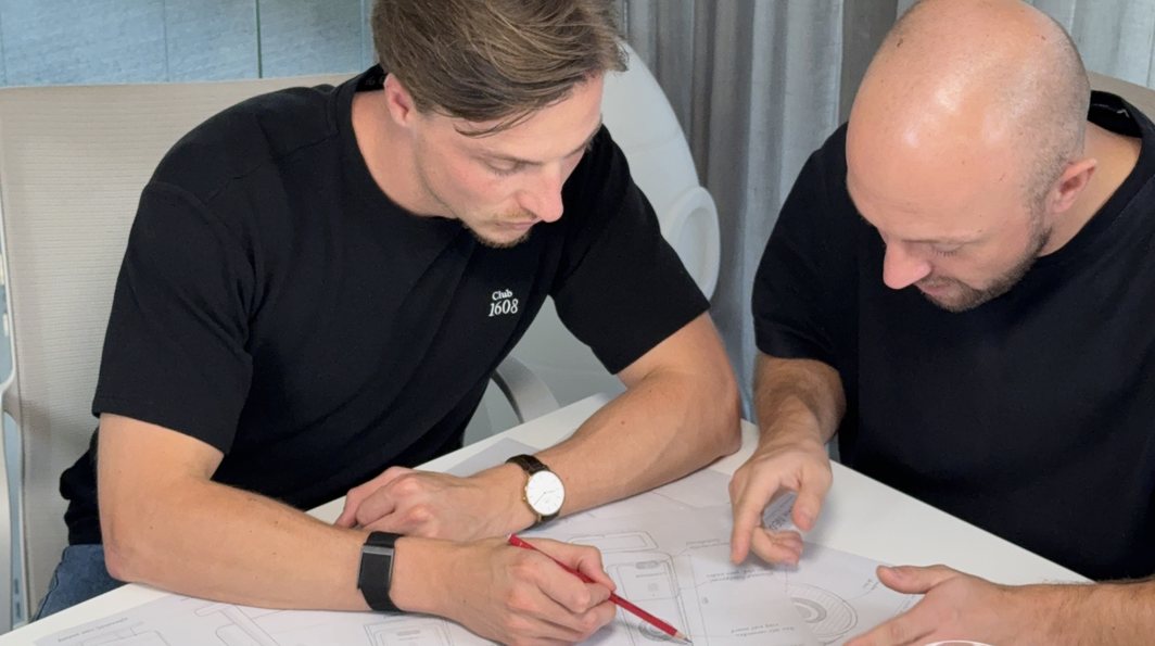 Dion en Maarten buigen zich over tekeningen van een beamer